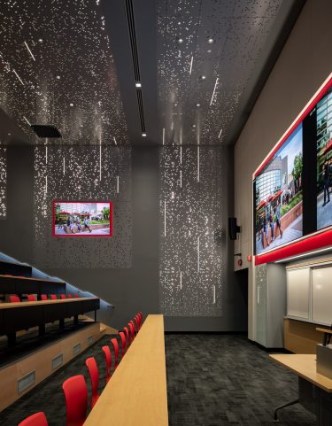 Lighting in the ceiling and walls penetrates the perforated metal panels reinforcing the “matrix” design theme.